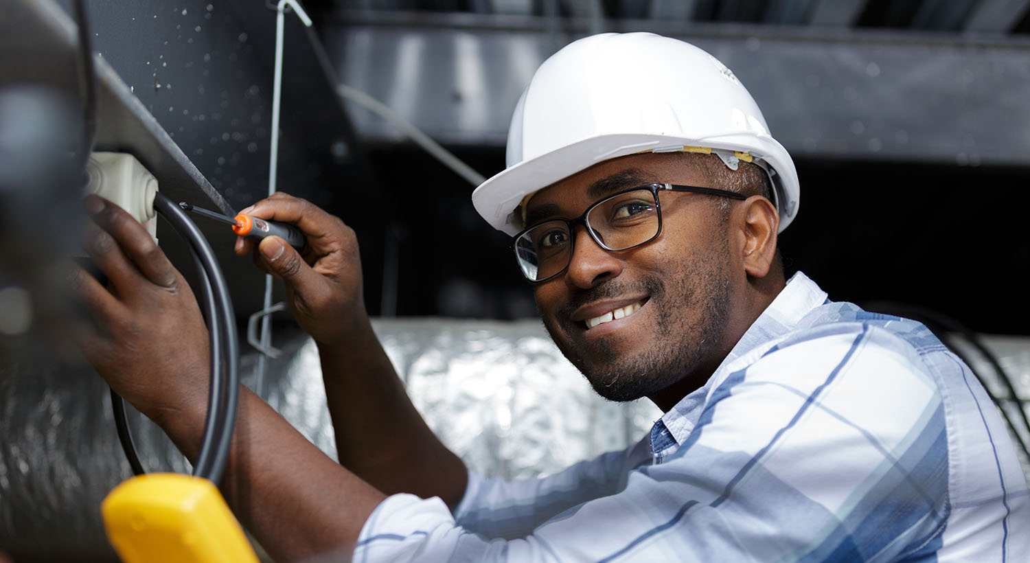 Black male with hard hat working on electrical panel