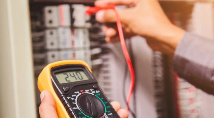 Electrician using a multimeter to test electrical circuits, a core skill taught at National Technical Institute