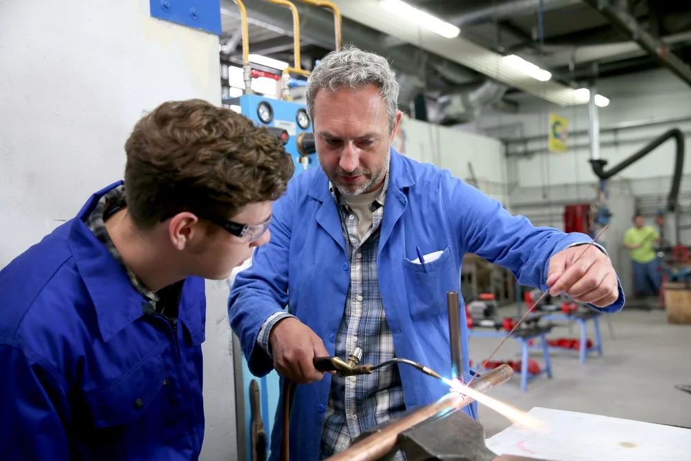 plumber showing his apprentice how to weld a pipe